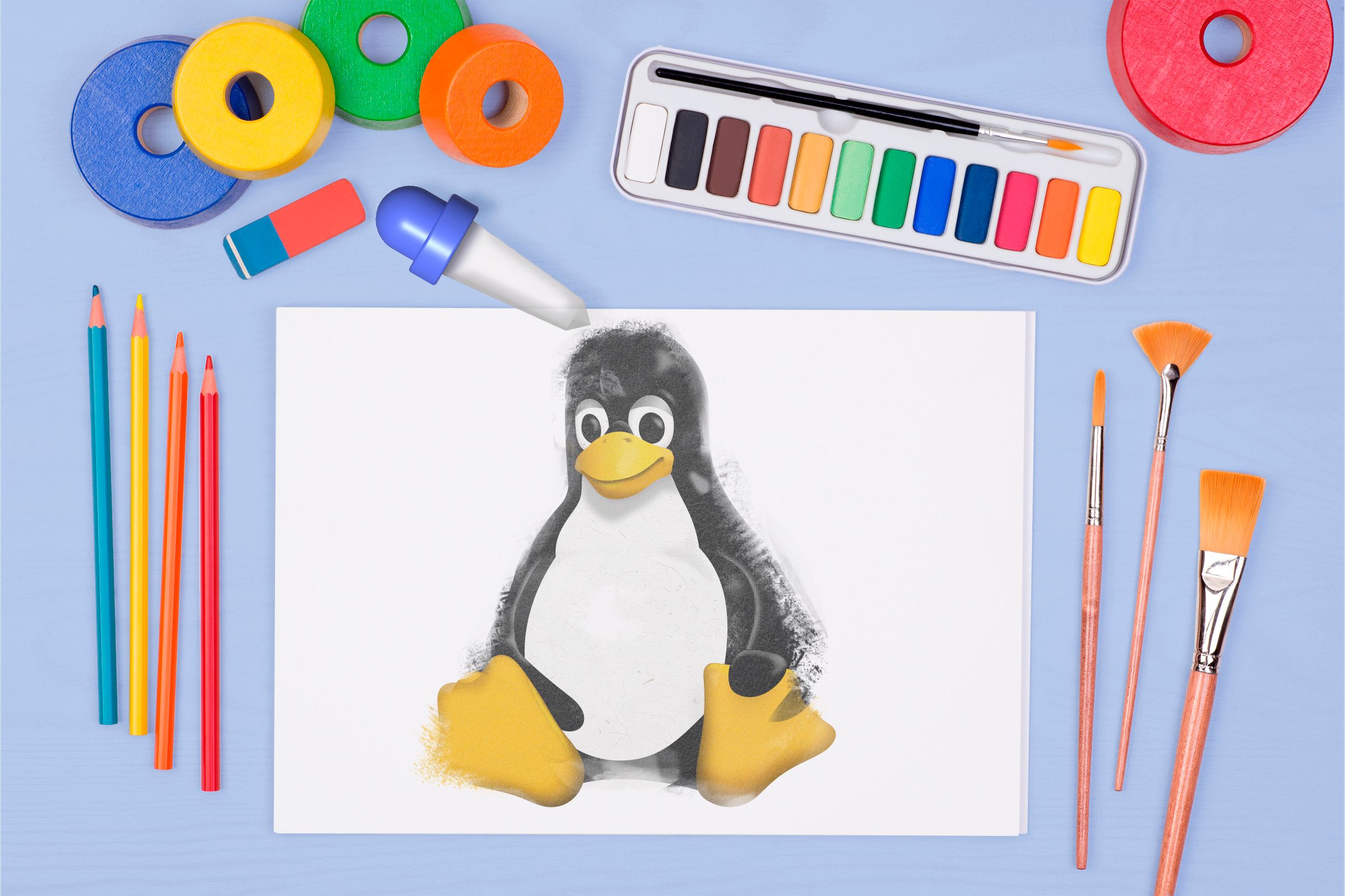 A sheet of paper with the Linux mascot and some drawing and painting items around it.