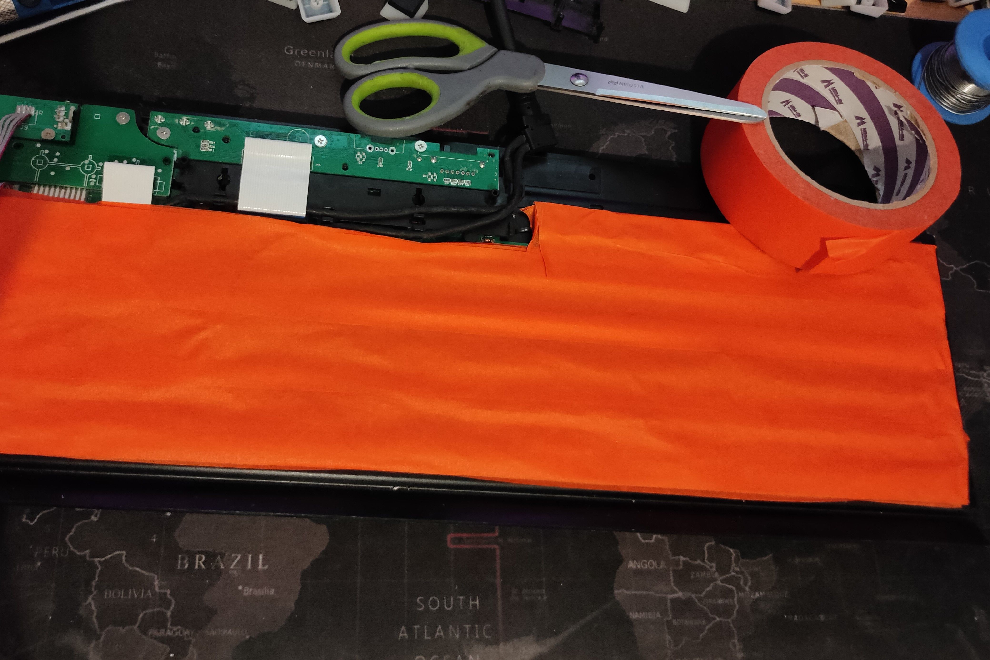 Orange painter's tape added to the back of a keyboard's PCB.