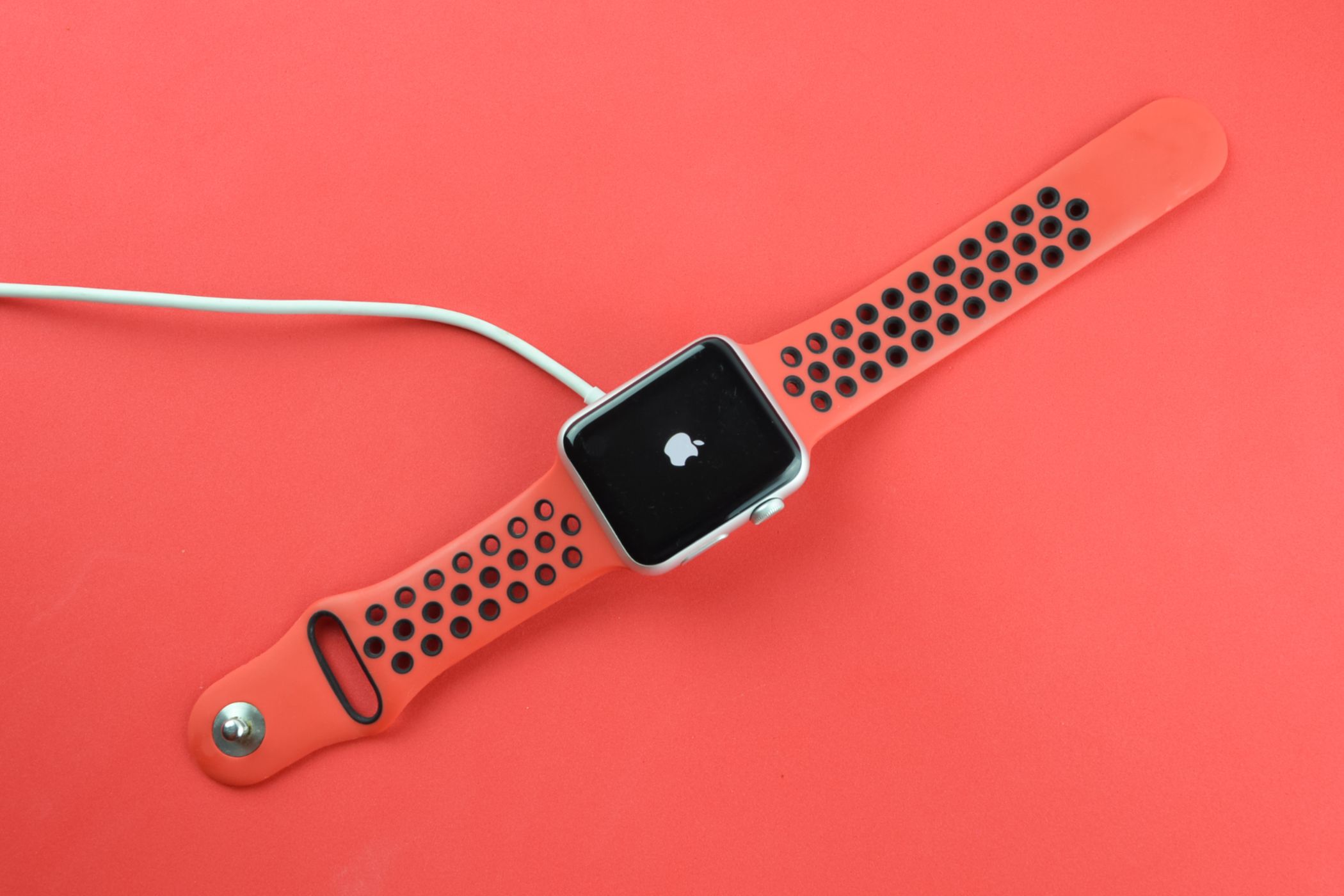 shutterstock_1837325308 Apple Watch connected to a charger displaying the Apple logo.