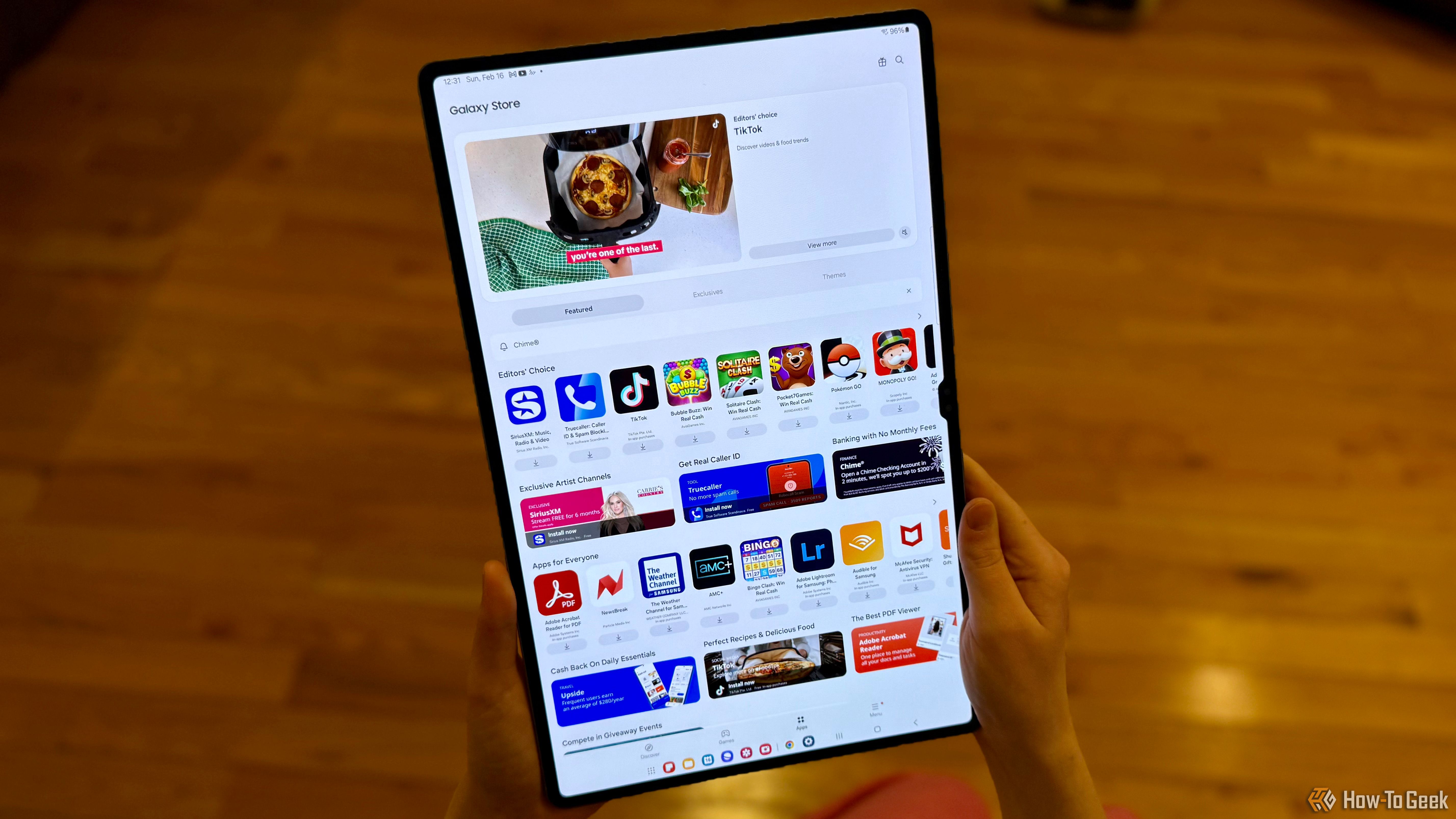 Holding a Samsung Galaxy Tab S10 Ultra showing the Galaxy Store.