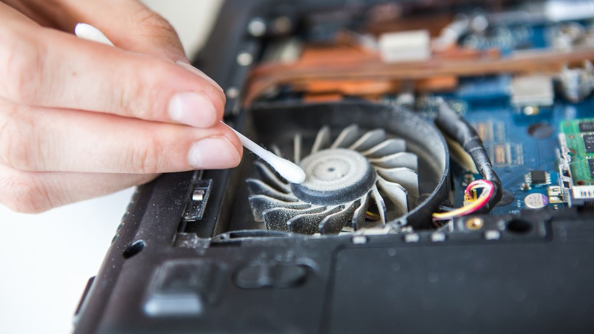 Person cleaning dust out of a laptop using a Q-Tip.