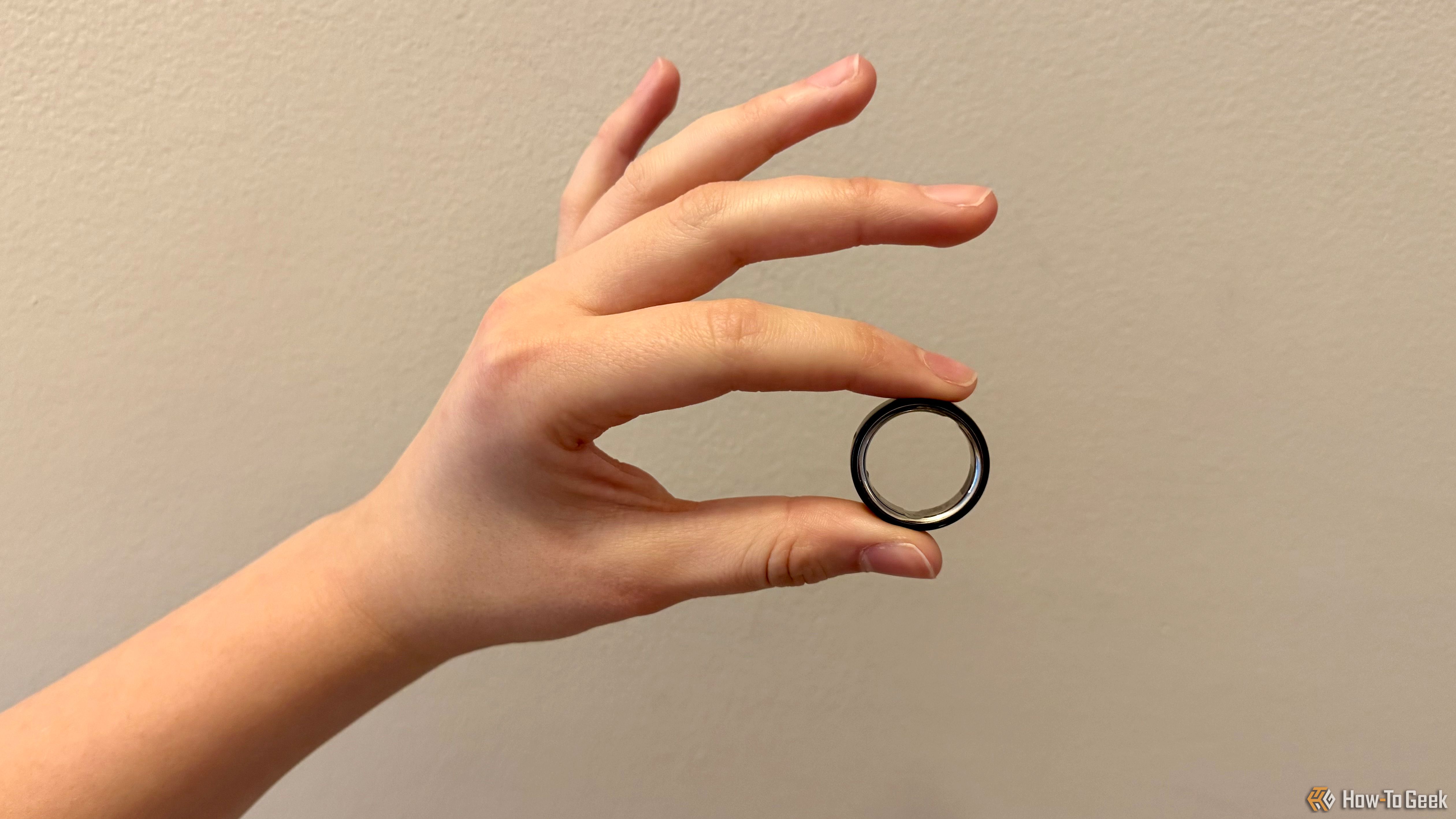 Oura Ring 4 being held between index finger and thumb.