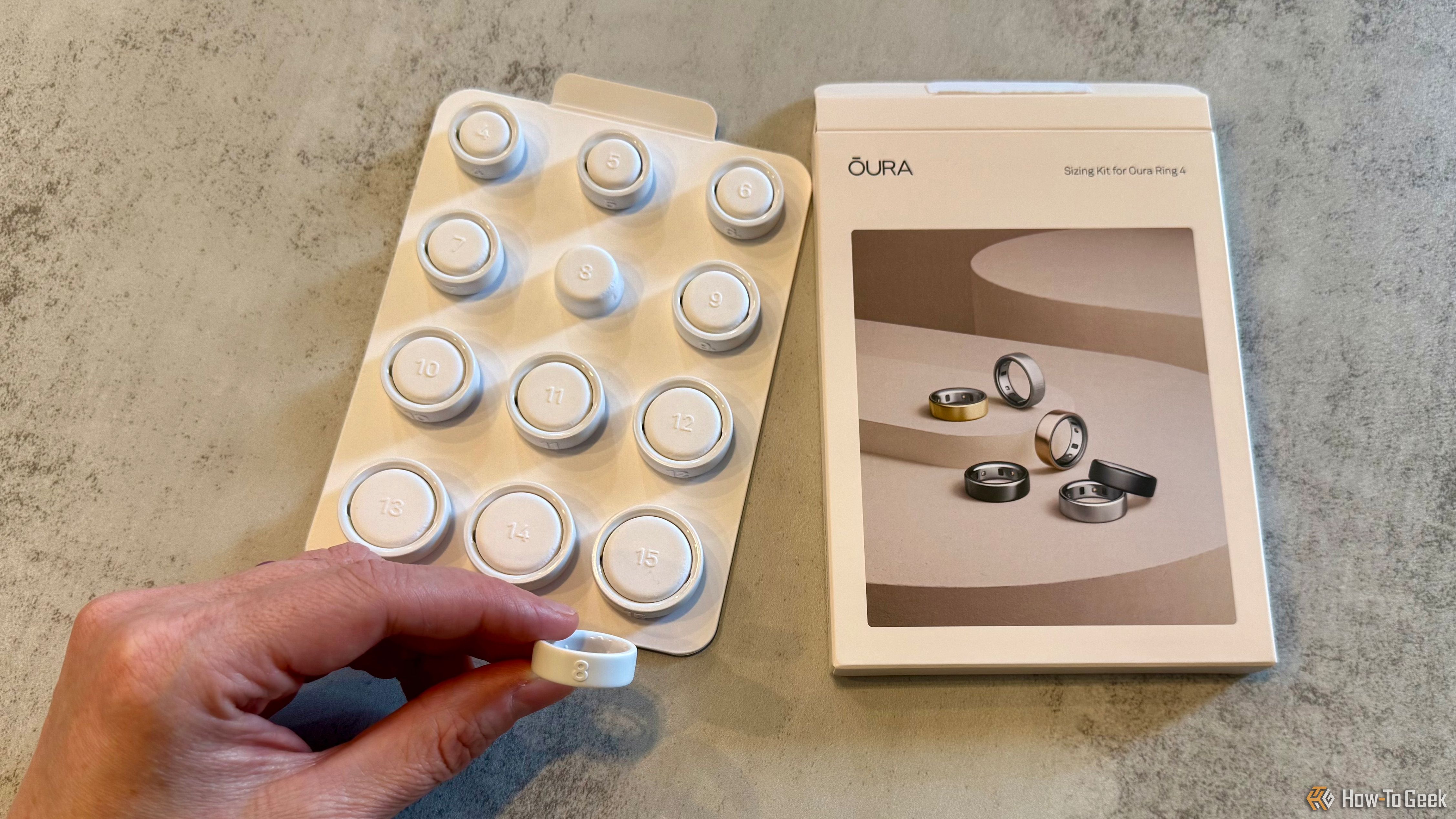 Oura Ring 4 sizing kit with one sizing ring being held.