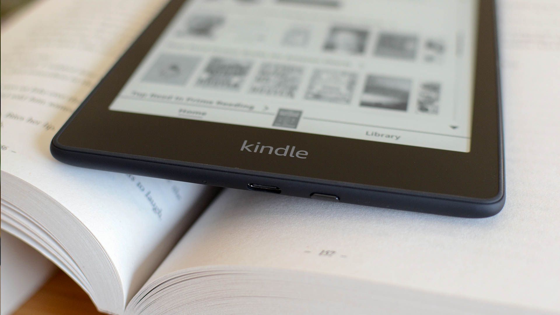 A Kindle ereader on top of a paper book.