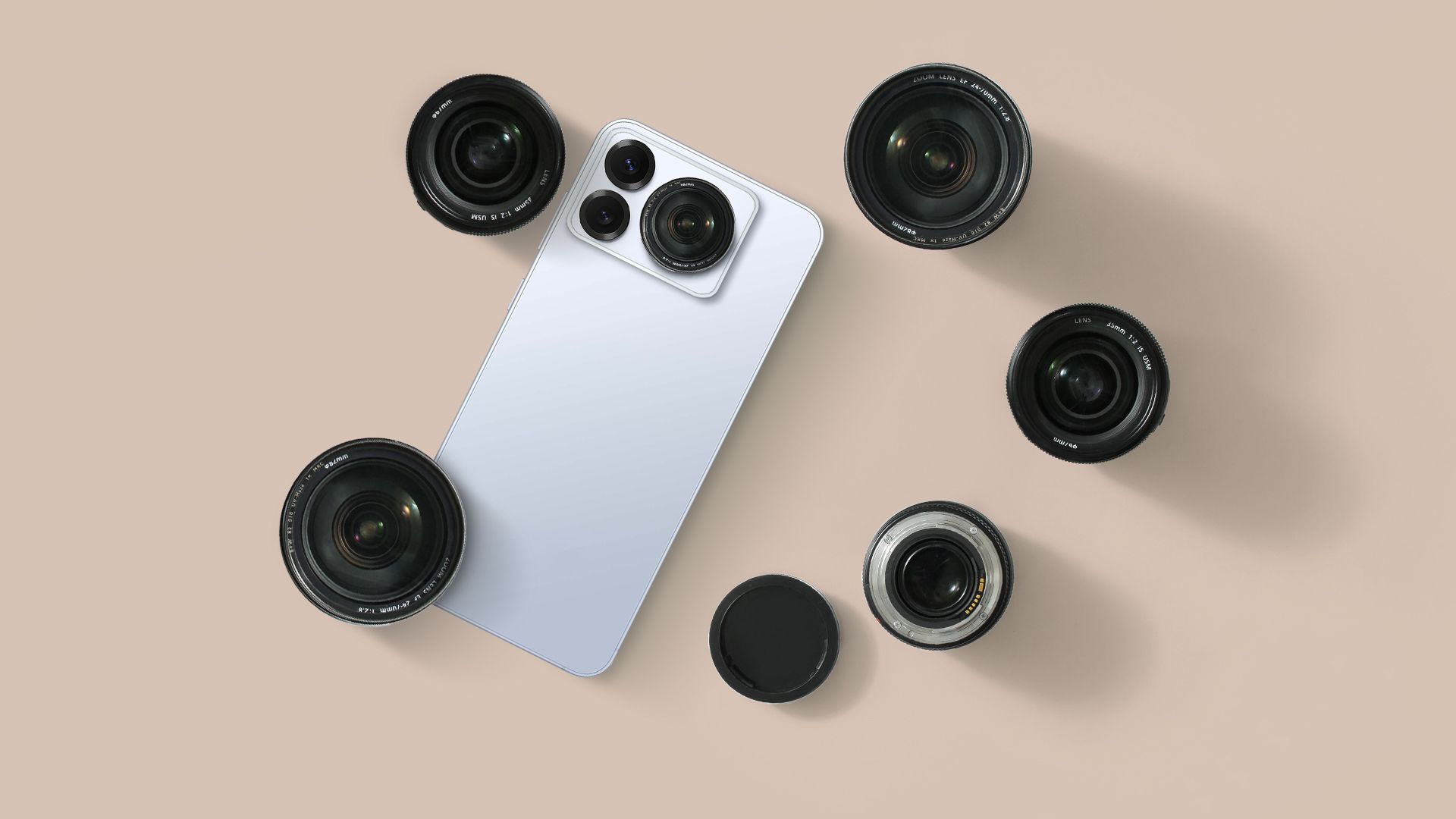 A smartphone next to some camera lenses.