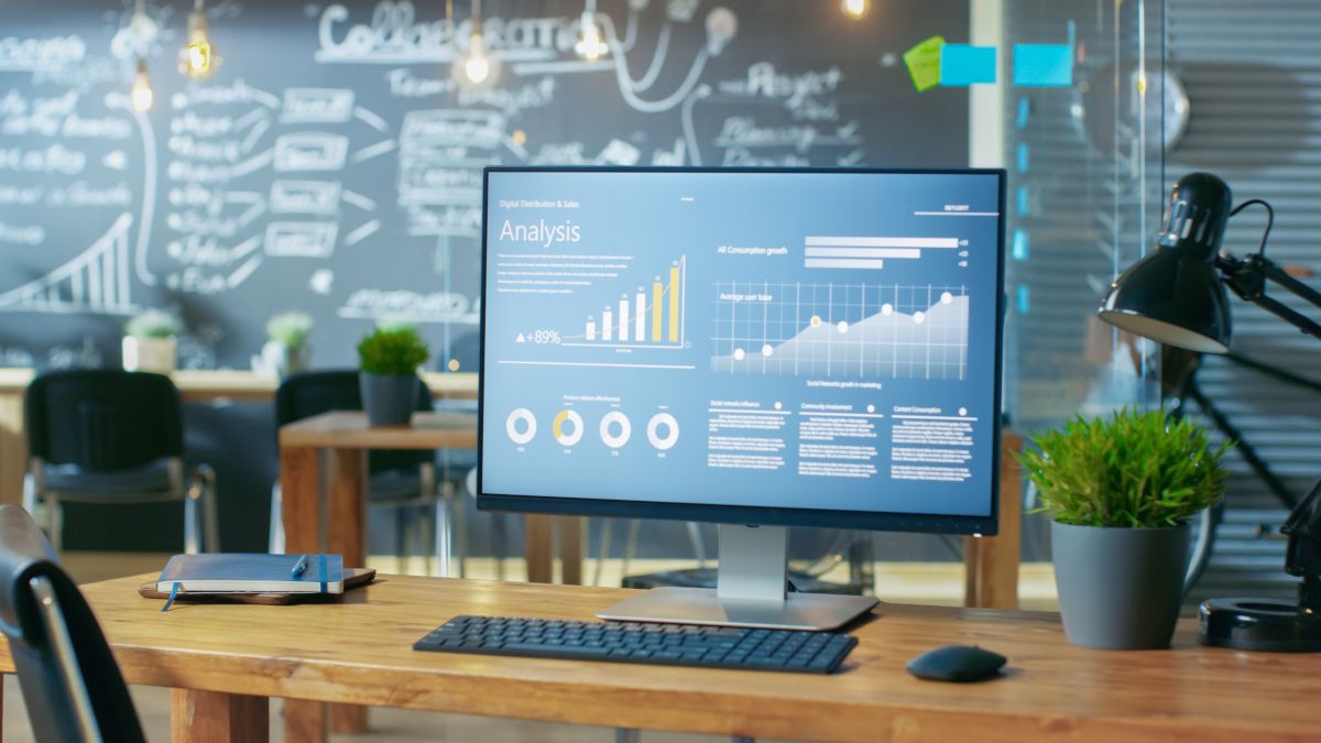 Computer on a desk in front of a chalkboard