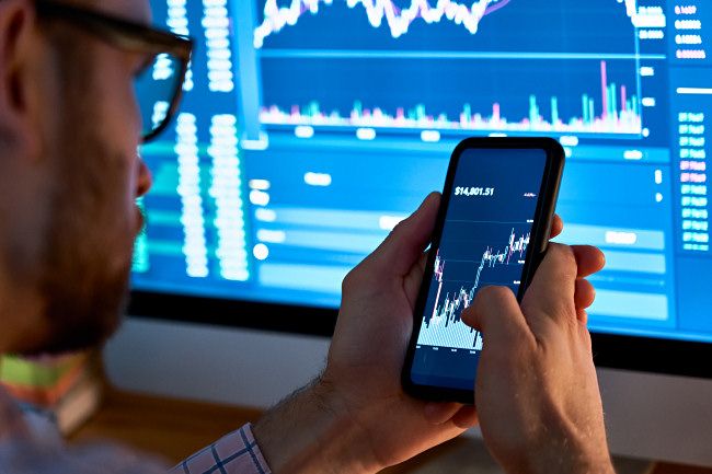 Man trading assets like stocks or crypto on smartphone