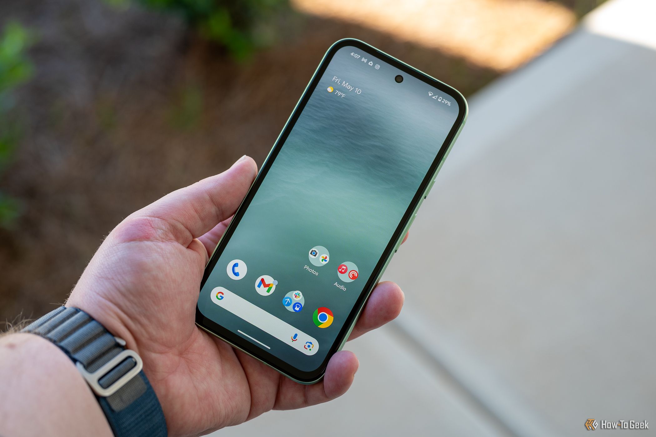 Person holding the Google Pixel 8a showing the home screen and bezels