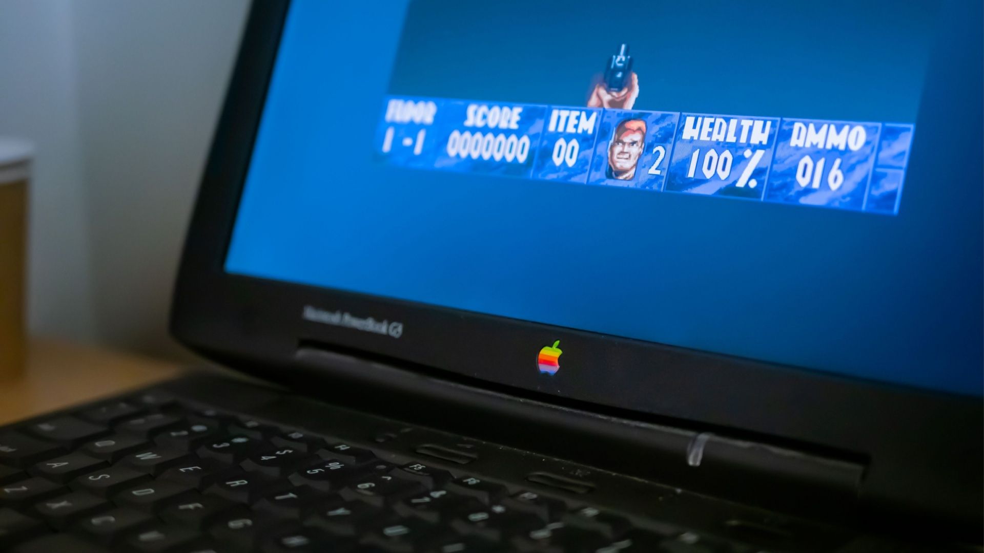 : Exhibition of old Apple laptop computers with retro video games in technology museum.