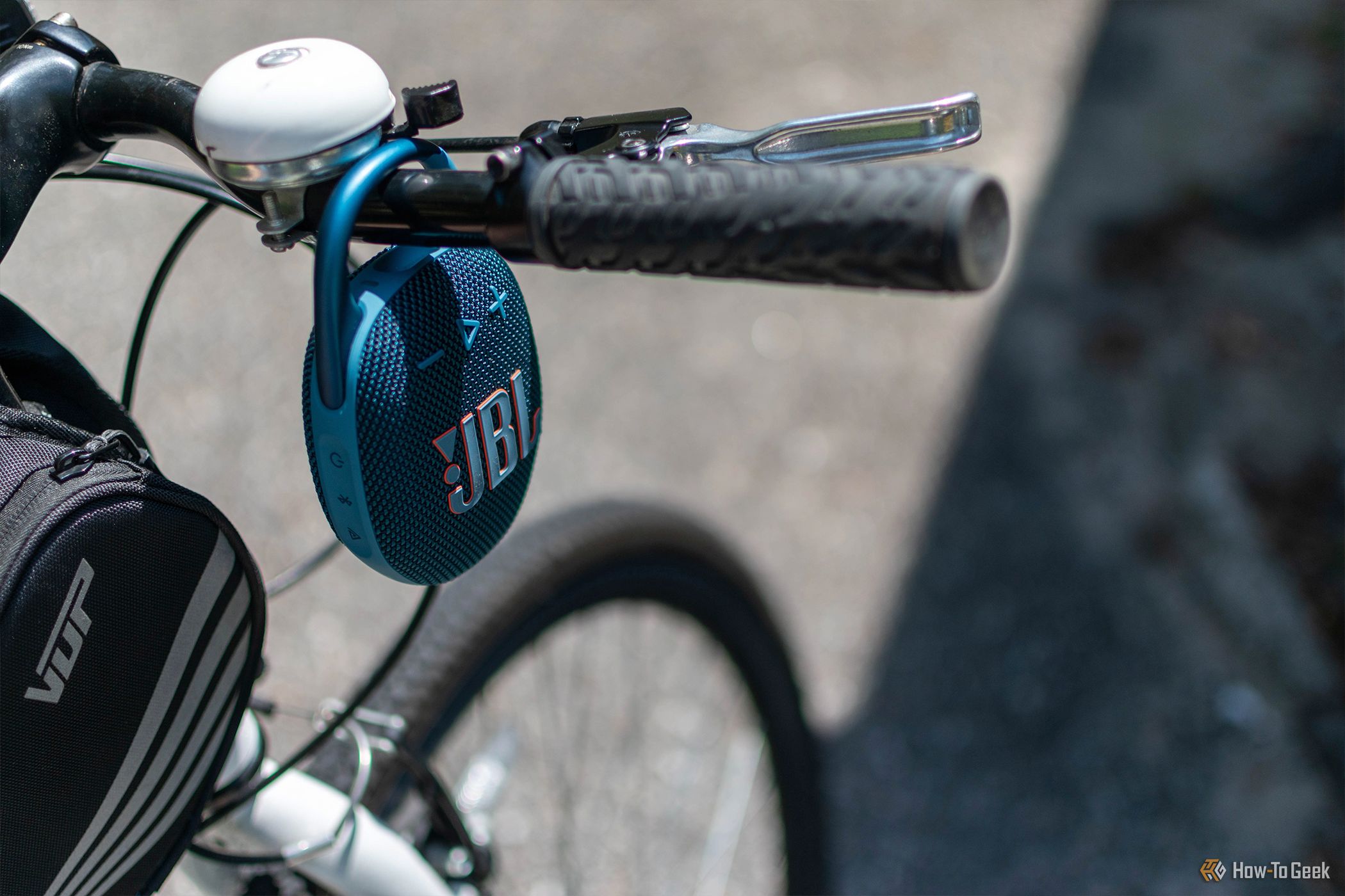 The JBL Clip 5 attached to a bike's handlebars.