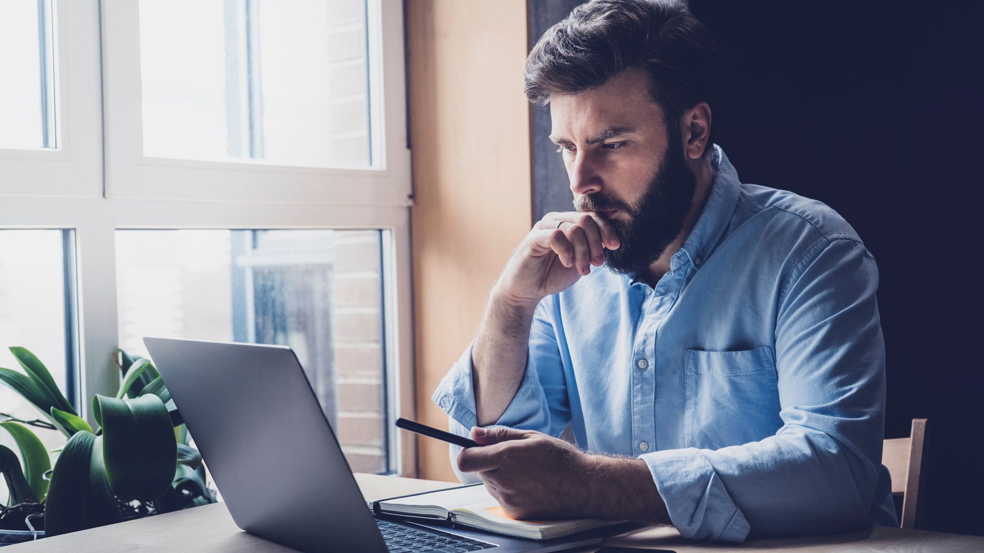 Man thinking and looking at a laptop.
