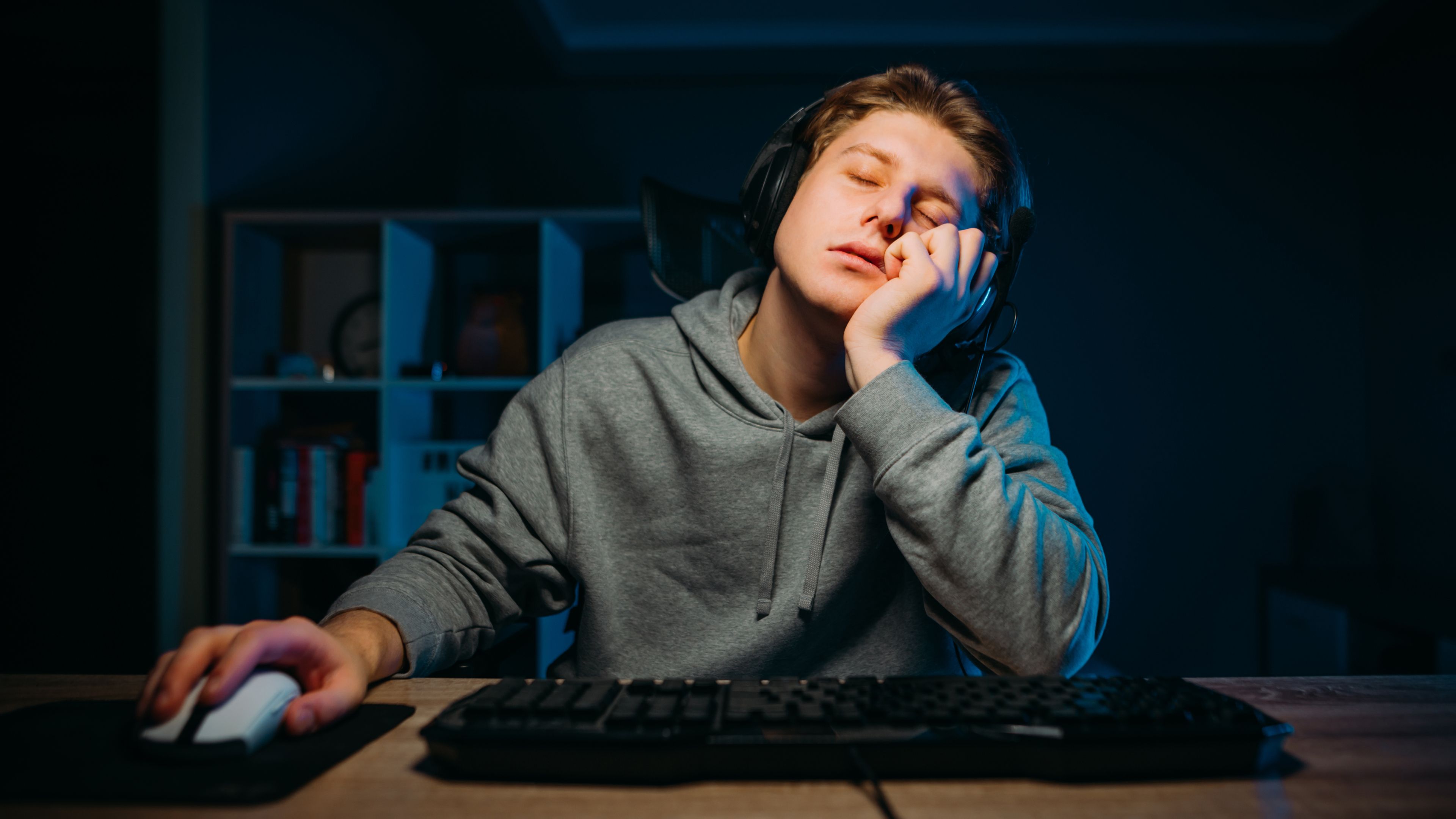 A bored and sleepy gamer sitting at their desk.