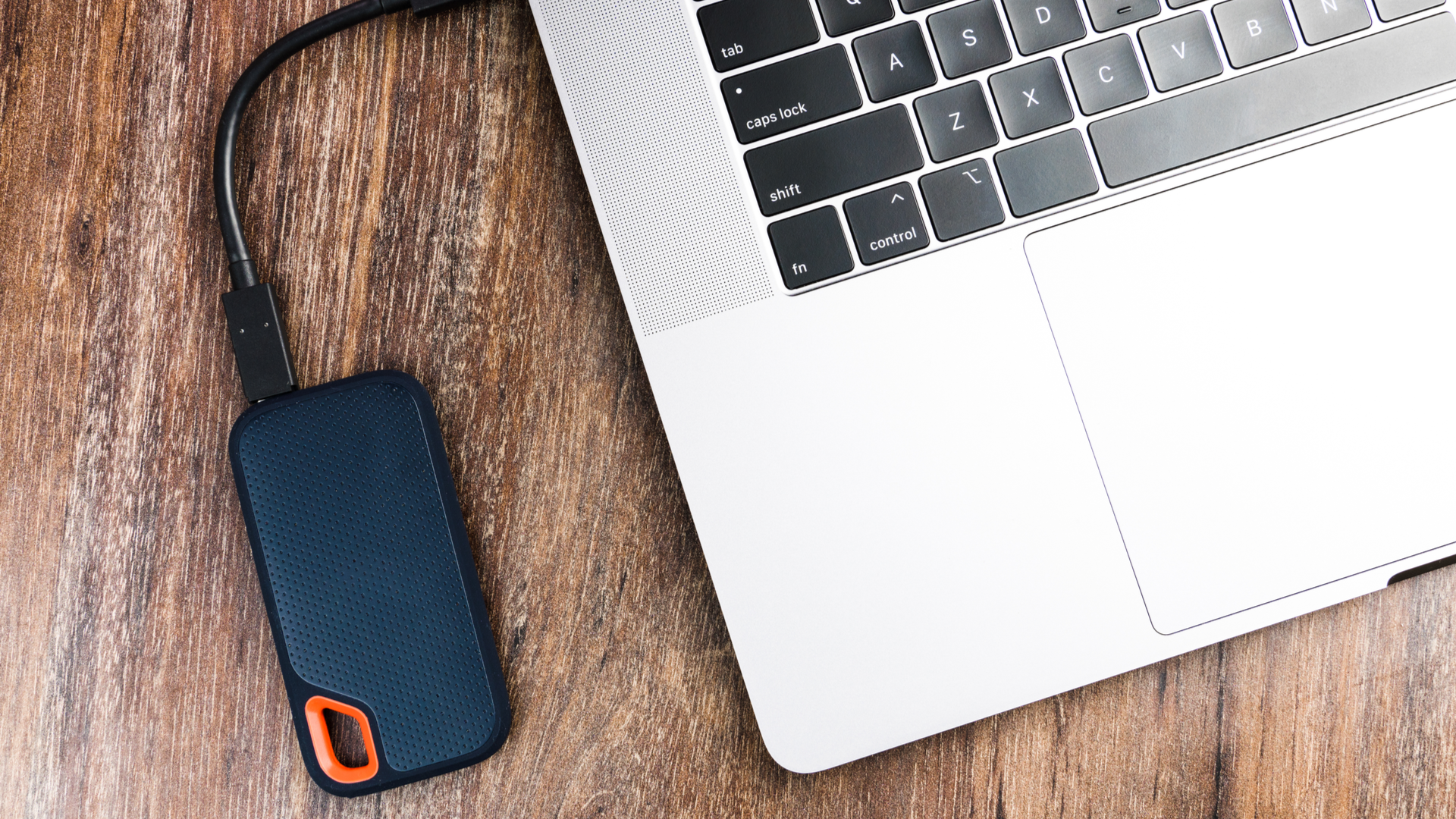 An external SSD Drive and a computer on wooden background.