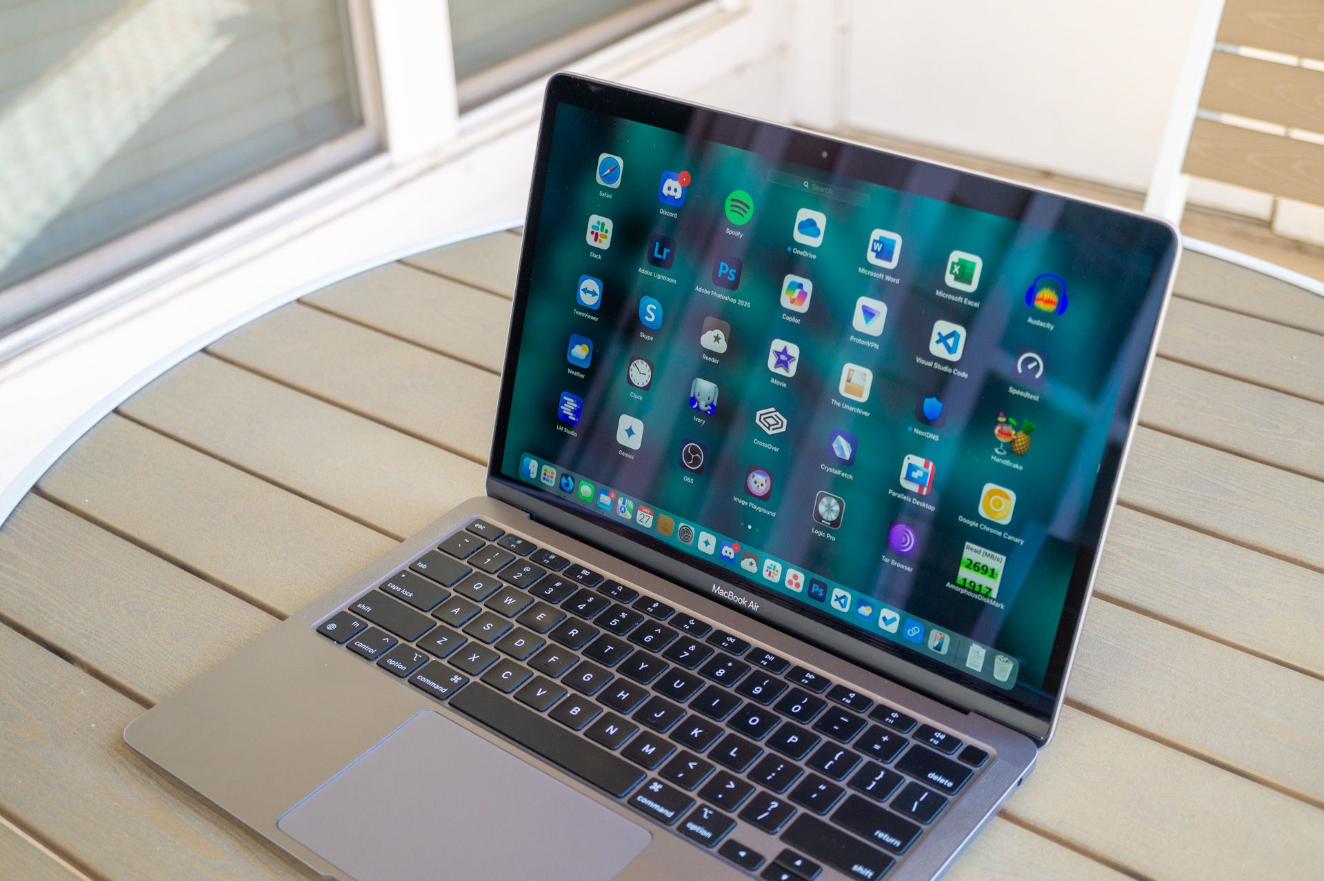 A MacBook Air with Launchpad open on a patio table.