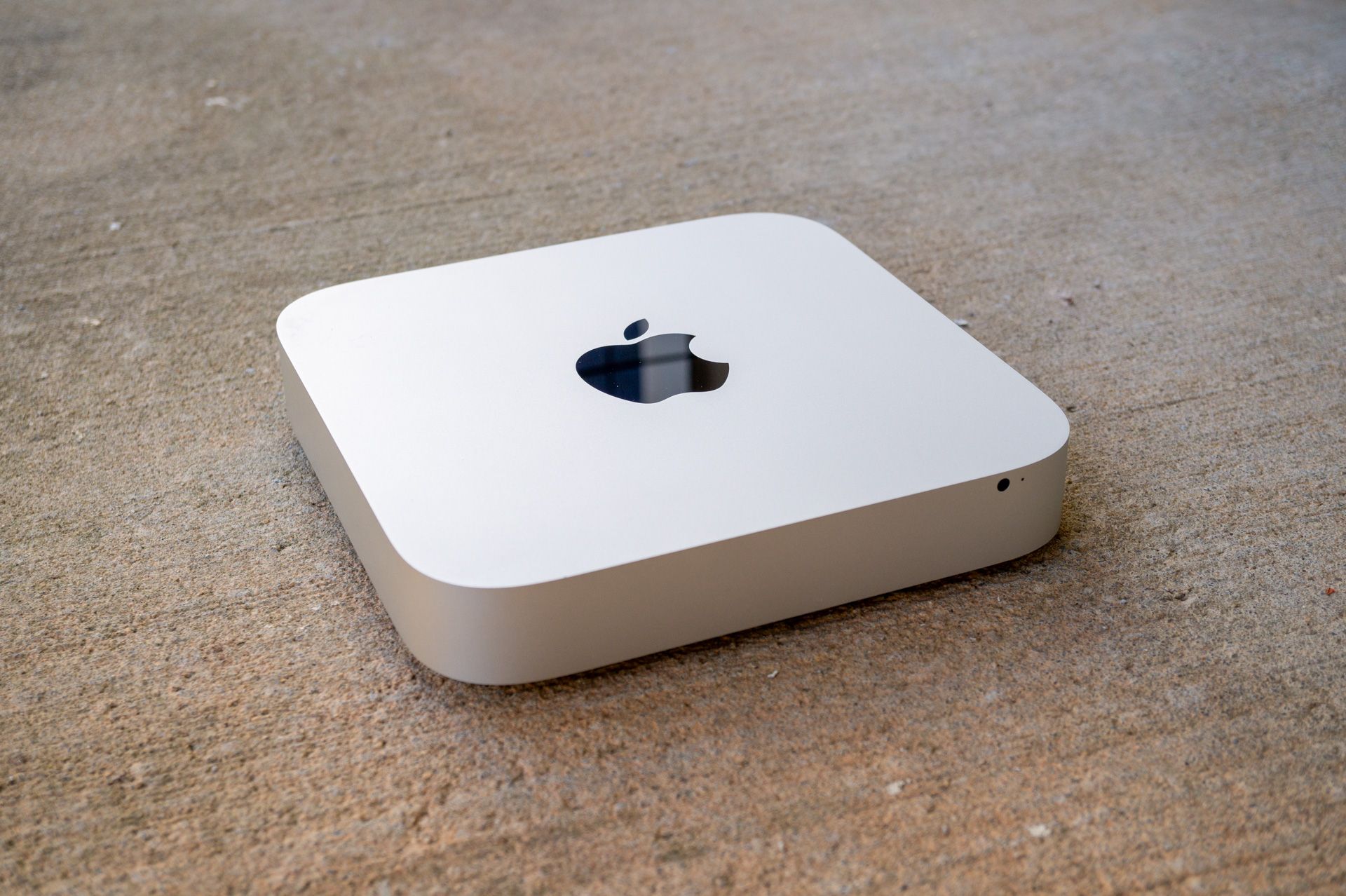 A Mac Mini computer on a concrete surface.