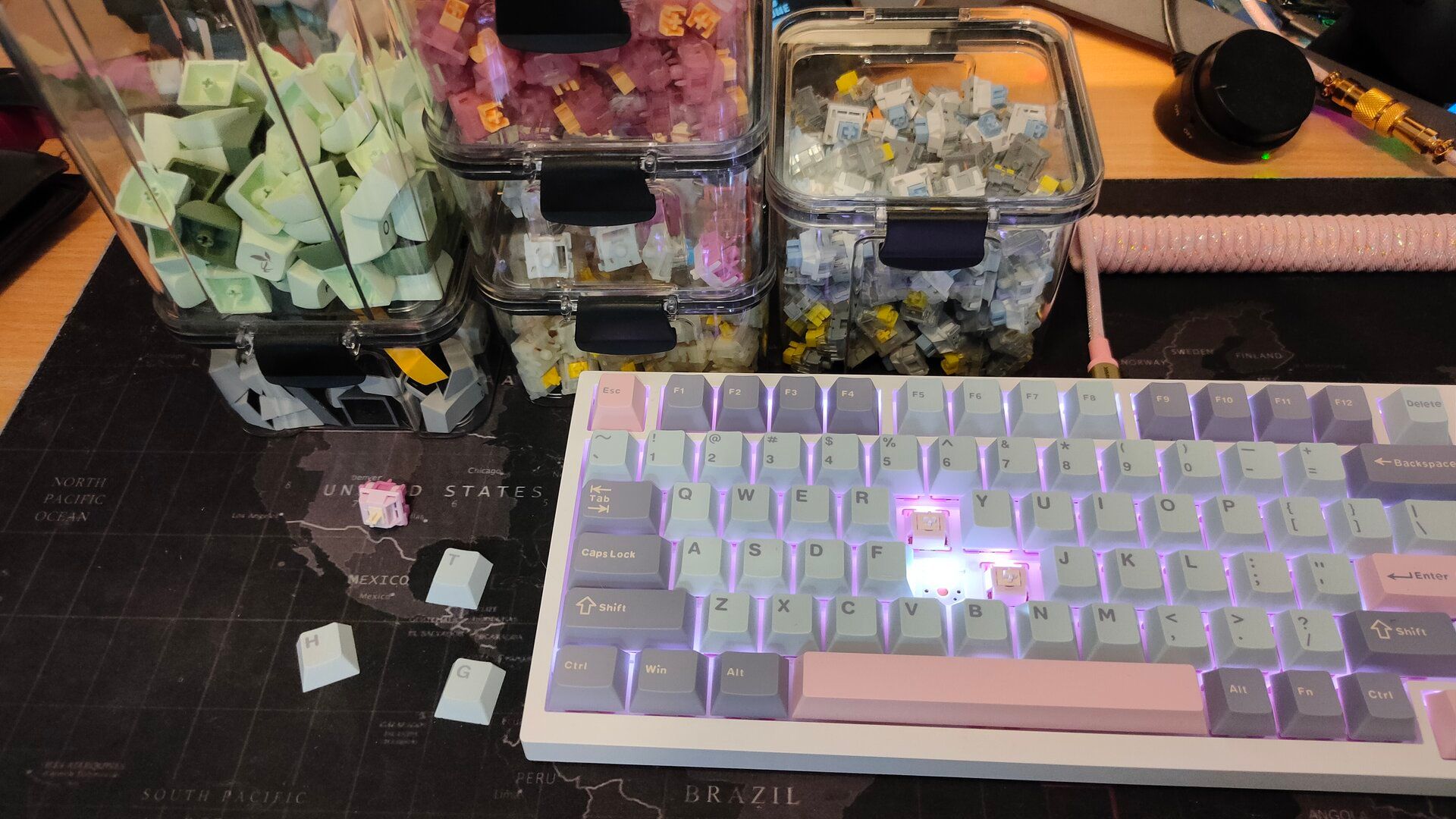 A custom keyboard with keycaps and switches in transparent boxes in the back.