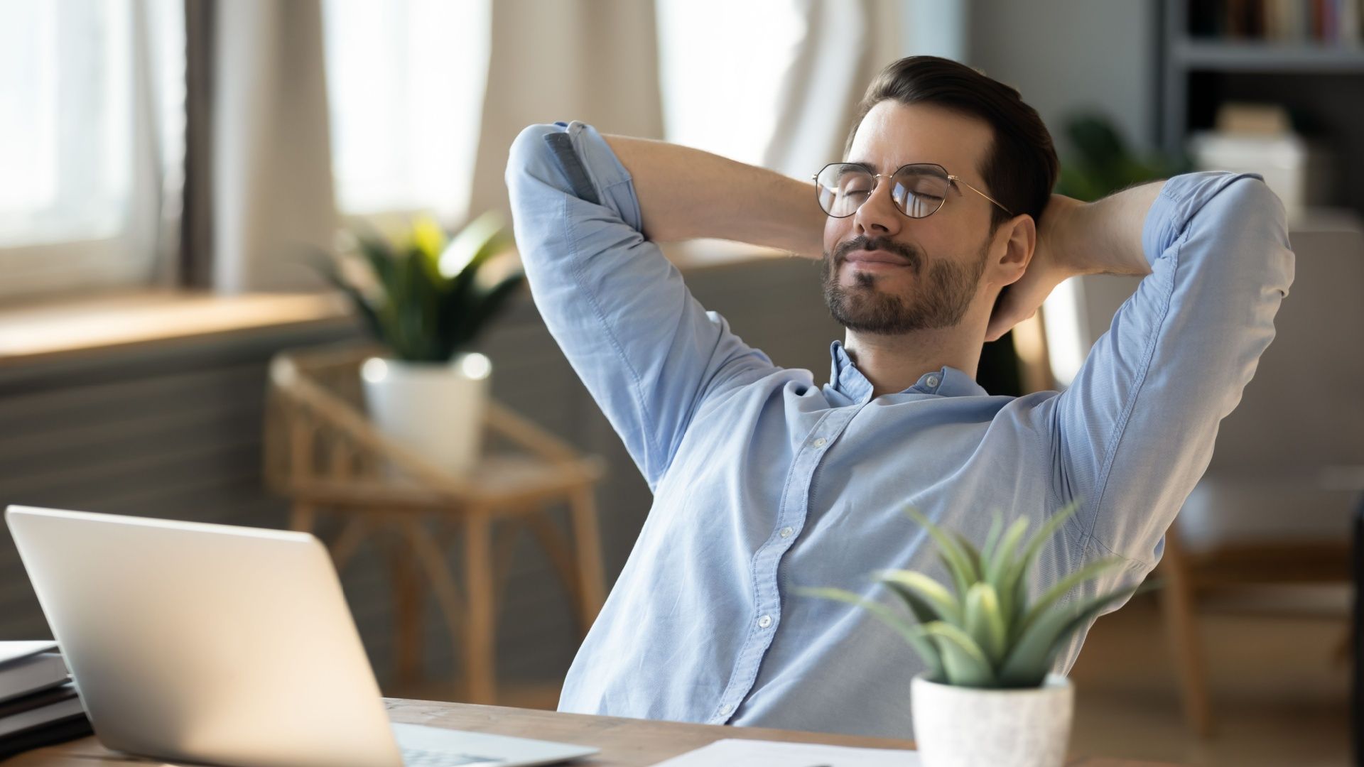 Calm millennial man in glasses sits and relaxes at home office.